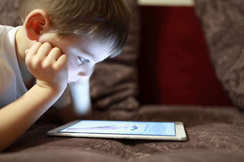 Child with tablet on sofa.