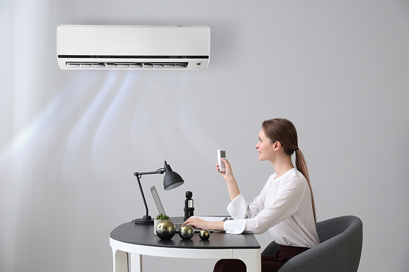 Woman using computer with air conditioner in the room.