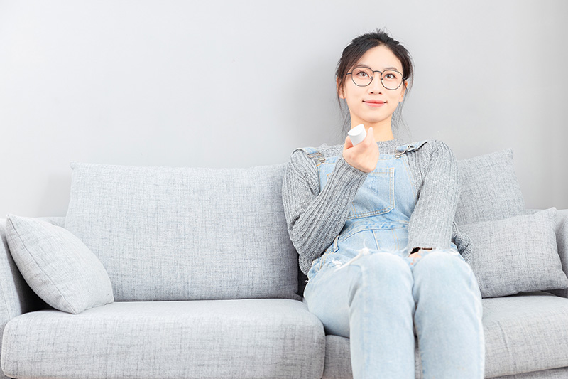 Woman sitting on a sofa, watching TV, relaxed and enjoying her leisure time.